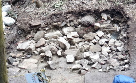 発掘調査でみつかった「破城」の痕跡 奥に大きめの石５つが横に並んでいるところが石垣のライン